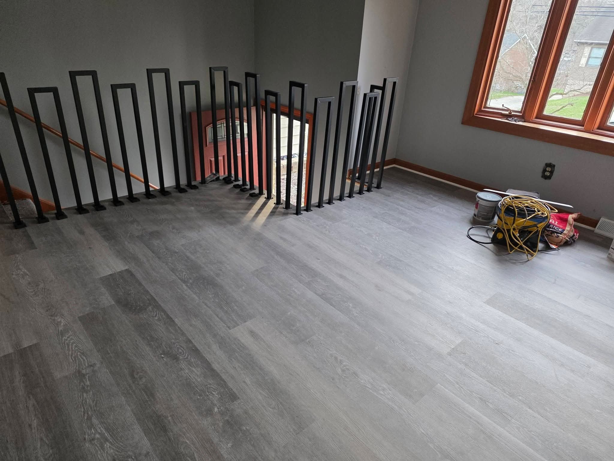 Room after — new vinyl plank flooring and black railing